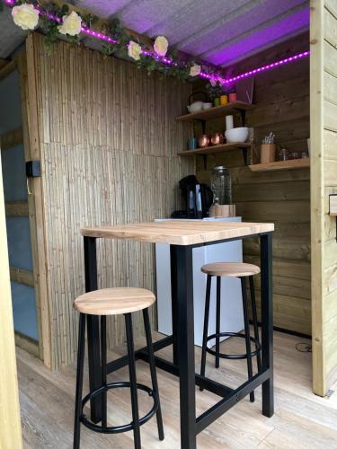 a bar with stools in a kitchen with purple lighting at Cabane au style scandinave et son bain nordique in Bouillon