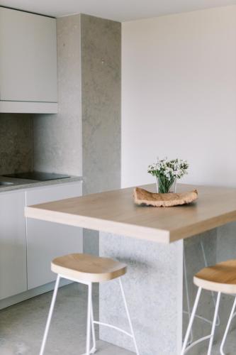 a kitchen with white cabinets and a counter with stools at The Editory By The Sea Troia Comporta Hotel in Troia