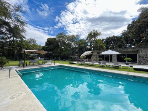 una piscina con sillas y sombrillas en Increíble casa familiar c/ alberca climatizada!, en Yautepec