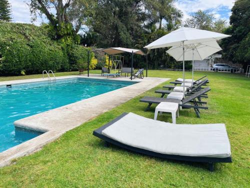 una piscina con un montón de sillas y una sombrilla en Increíble casa familiar c/ alberca climatizada!, en Yautepec