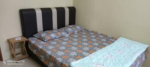 a bed with a blue comforter and pillows on it at *IA D'CHATIN HOMESTAY MENTAKAB* in Mentekab