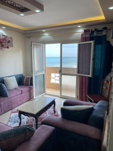a living room with couches and a view of the ocean at Alzohour Family condo with panoramic sea view in Alexandria