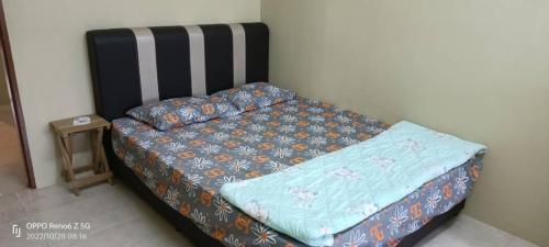 een bed met een blauw dekbed en kussens erop bij *IA D'CHATIN HOMESTAY MENTAKAB* in Mentekab