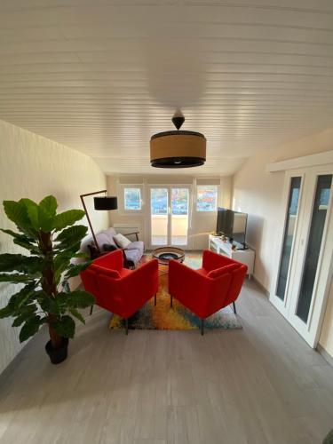 un salon avec deux chaises rouges et une table dans l'établissement My Noï Home, à Arcachon