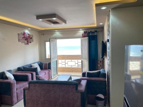 a living room with couches and a view of the ocean at Alzohour Family condo with panoramic sea view in Alexandria