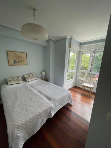 a bedroom with a white bed with a wooden floor at Azaraleku apartamento playa in Zarautz