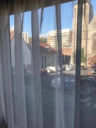 a view of a street from a window with curtains at Appartement centre ville in Tournai