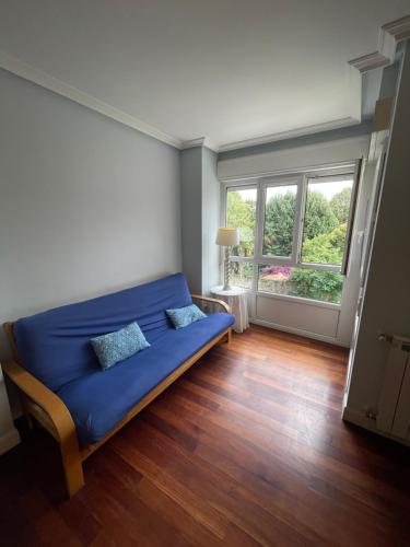 a blue couch in a room with a window at Azaraleku apartamento playa in Zarautz