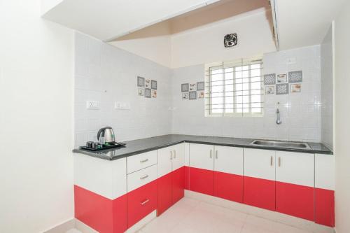 a kitchen with red and white cabinets and a sink at Pristine Inn Manyata in Bangalore