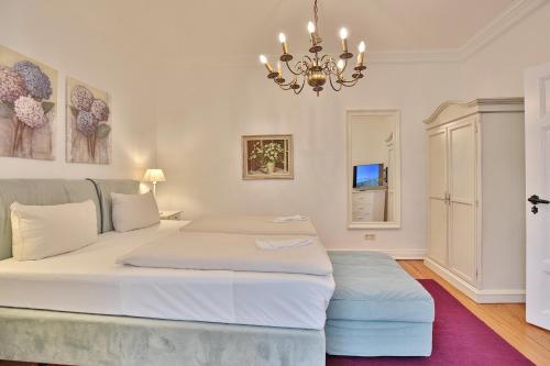 een slaapkamer met een groot wit bed en een kroonluchter bij Villa Schöneck Villa Schöneck Appartement 2 in Scharbeutz