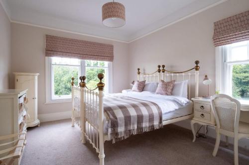 a white bedroom with a white bed and two windows at Surrey Lodge in Brockenhurst