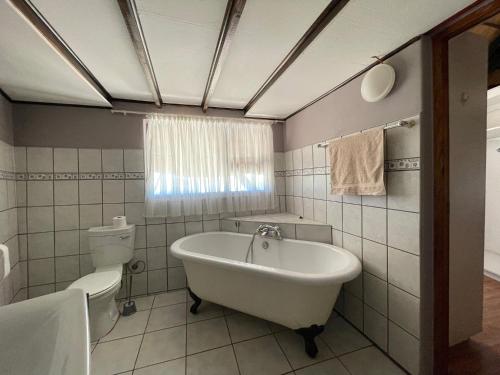 La salle de bains blanche est pourvue d'une baignoire et de toilettes. dans l'établissement Privathaus mit eigenem Pool - Windhoek, à Windhoek