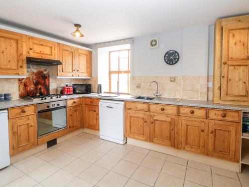 a large kitchen with wooden cabinets and white appliances at The Tom Wragg Suite in Bakewell