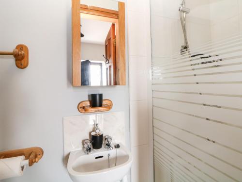 ein Bad mit einem Waschbecken und einem Spiegel in der Unterkunft The Tom Wragg Suite in Bakewell