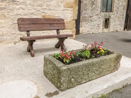 a wooden bench sitting next to a stone planter with flowers at The Tom Wragg Suite in Bakewell