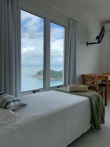 a bedroom with a large window with a view of the ocean at Guesthousebr in Bombinhas