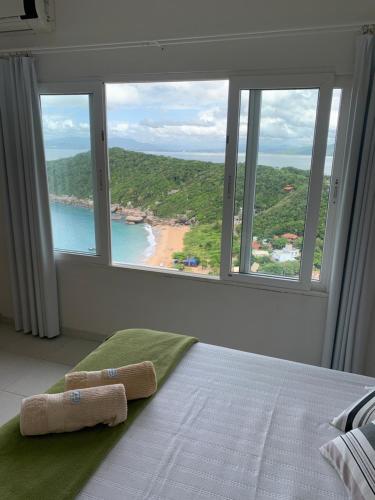 a bedroom with a bed with a view of a beach at Guesthousebr in Bombinhas