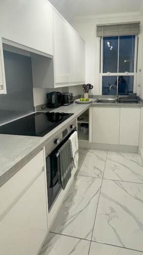 a white kitchen with white cabinets and a window at Cosy & Comfortable - Heart of Hove - Beach Getaway in Brighton & Hove
