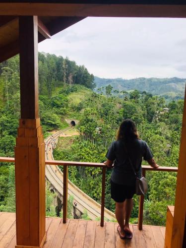 a woman standing on a balcony looking at a train track at Green Nature Paradise Ella in Ella