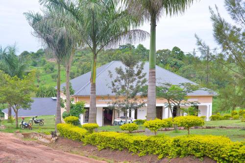 una casa con palmeras delante en Katente Country Resort, en Kyegegwa