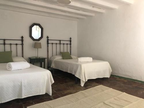 a room with two beds and a mirror on the wall at Casa del Almezo in Almodóvar del Río