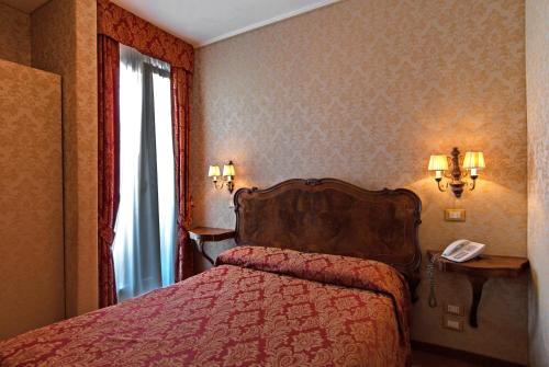 a bedroom with a bed and a phone and a window at Hotel Bel Sito e Berlino in Venice