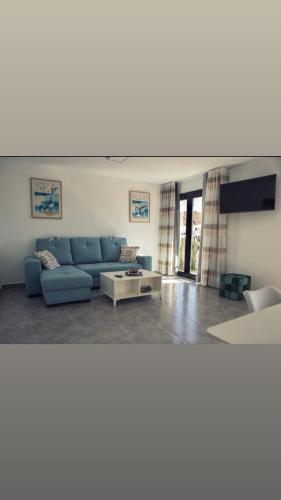 ein Wohnzimmer mit einem blauen Sofa und einem Tisch in der Unterkunft El Rincón de Agua Amarga 2 in Agua Amarga