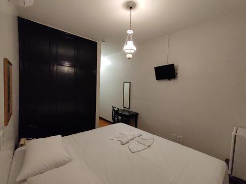 um quarto com uma cama branca e uma porta preta em Hotel Itarare em Itararé