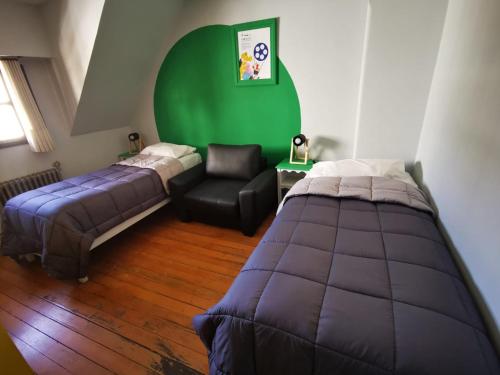 a bedroom with two beds and a green wall at Cinerama Hostel in San Carlos de Bariloche