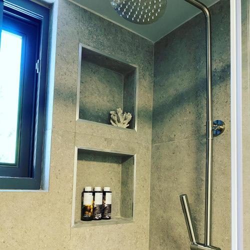 a bathroom with a shower with three bottles of soap at no.21house. Α Beach house in Rio,Patras in Rio