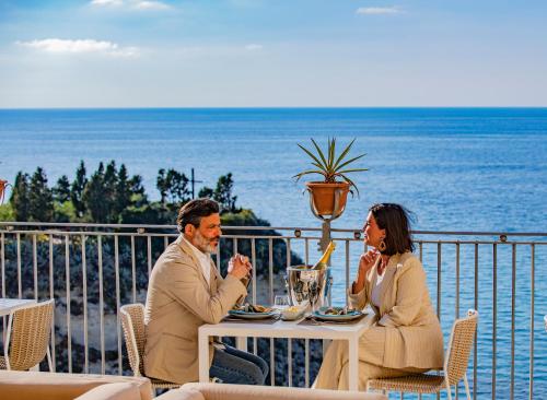 a man and woman sitting at a table near the ocean at La Dolce Vita a Tropea in Tropea