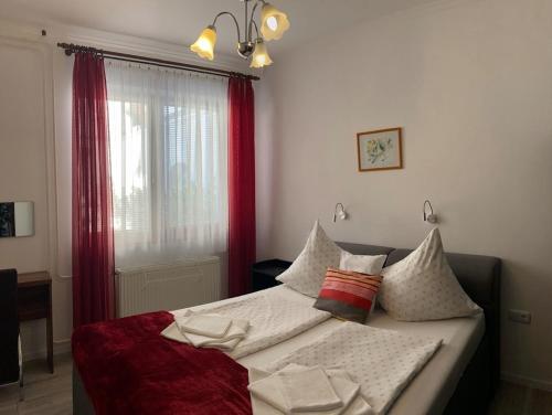 1 dormitorio con cama con almohadas y ventana en Bathory Apartments, en Hajdúszoboszló