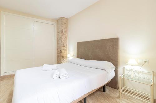 1 dormitorio con 1 cama blanca grande y toallas. en Allo Apartments Consistorio Centro 2 Habitaciones, en Jerez de la Frontera