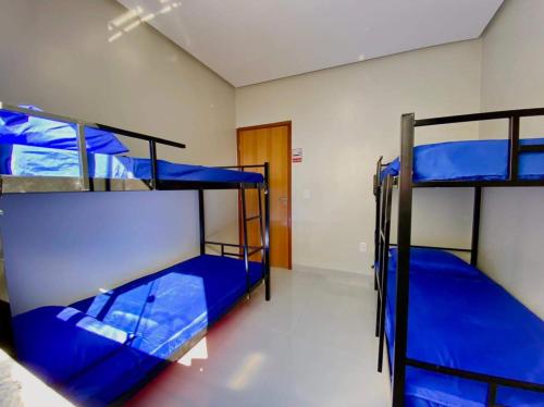 a room with three bunk beds with blue sheets at Hostel Flor de Carajás in Parauapebas