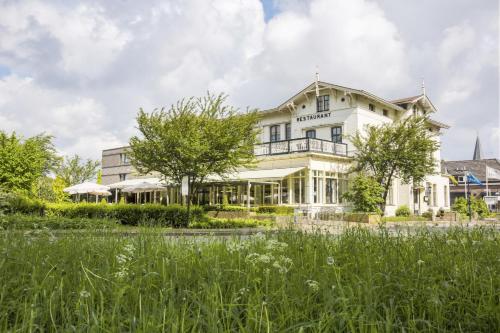 a large white house with a lawn in front of it at Hampshire Hotel - Avenarius in Ruurlo