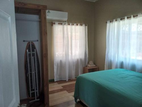a bedroom with a green bed and a window at Cozy 2 bedroom beachfront cabin in Canouan
