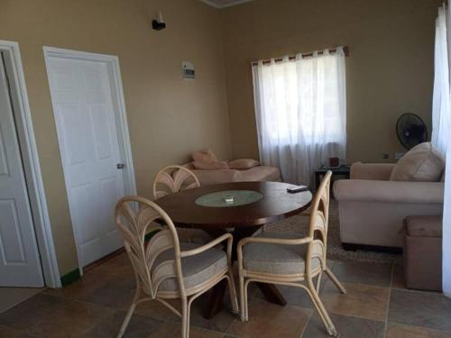 a living room with a table and chairs and a couch at Cozy 2 bedroom beachfront cabin in Canouan