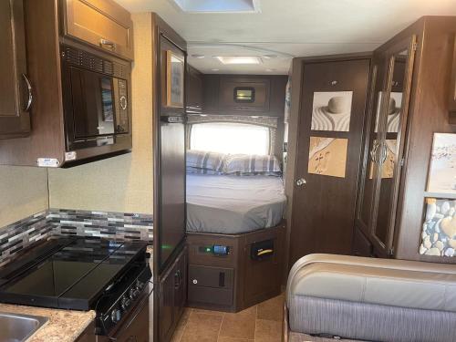 uma pequena cozinha com uma cama num trailer em AJ-XL RV Rental em Reseda