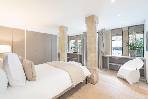 a bedroom with a white bed and a white chair at Knightsbridge Large Luxury Flat With Outside Space in London