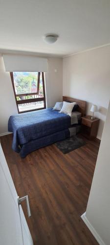 um quarto com uma cama azul e uma janela em Departamento vacacional em Villarrica
