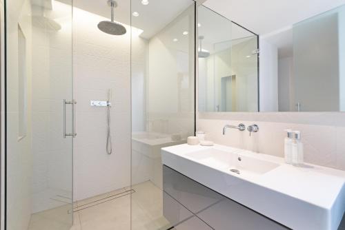 a bathroom with a sink and a glass shower at Knightsbridge Large Luxury Flat With Outside Space in London