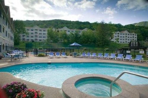 a large swimming pool with chairs and a building at Unique Yeti-Theme Ski On Off Suite Jiminy-Sleeps 4 in Hancock