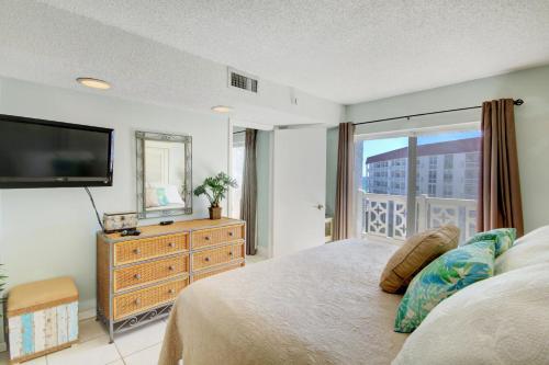 een slaapkamer met een groot bed en een televisie bij El Matador 358 - Beautiful views of the Gulf and pool in Fort Walton Beach