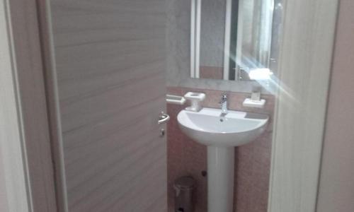 HOTEL Via Emilia Ovest 224 SELF CHECK-IN في بارما: حمام مع حوض أبيض ومرآة
