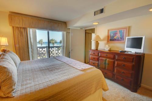 1 dormitorio con cama y vestidor con TV en El Matador 437 - Gulf front with beautiful views of the Gulf and pool, en Fort Walton Beach