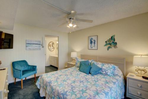 ein Schlafzimmer mit einem Bett und einem blauen Stuhl in der Unterkunft El Matador 443 - Beautiful views of the pool and Gulf of Mexico in Fort Walton Beach