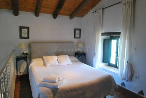 a bedroom with a large white bed with a window at Finca La Vicaria PALOMAR in Zufre
