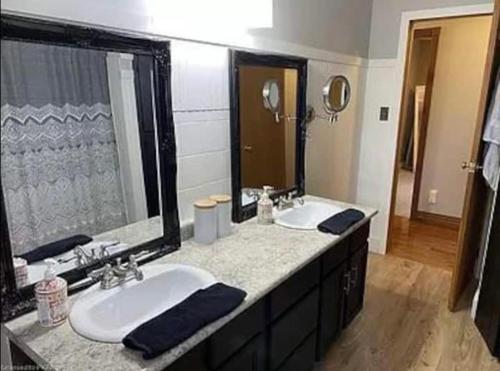 a bathroom with two sinks and a large mirror at Bancroft Petals I Sleep 9 l BBQ in Bancroft