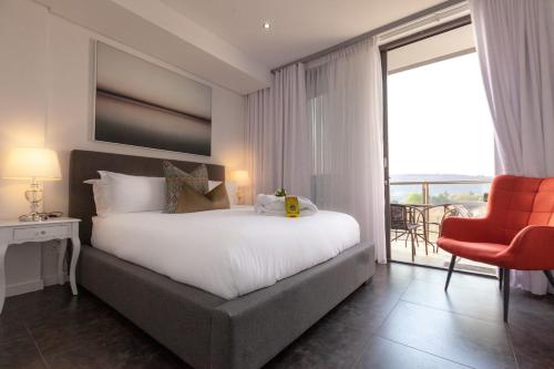een slaapkamer met een groot bed en een rode stoel bij Delight Infinity Apartments in Johannesburg