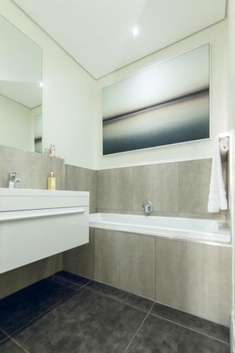 uma casa de banho com uma banheira, um lavatório e um espelho. em Delight Infinity Apartments em Joanesburgo